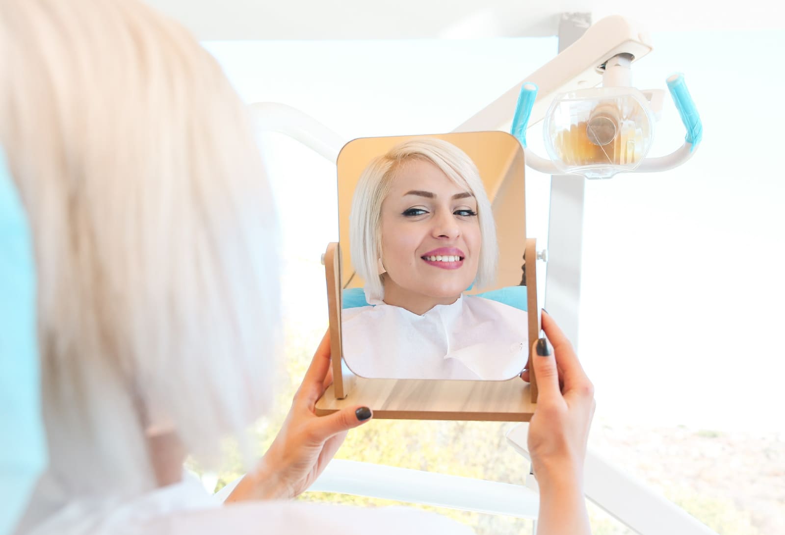 A patient seeing their new smile in a mirror at the clinic